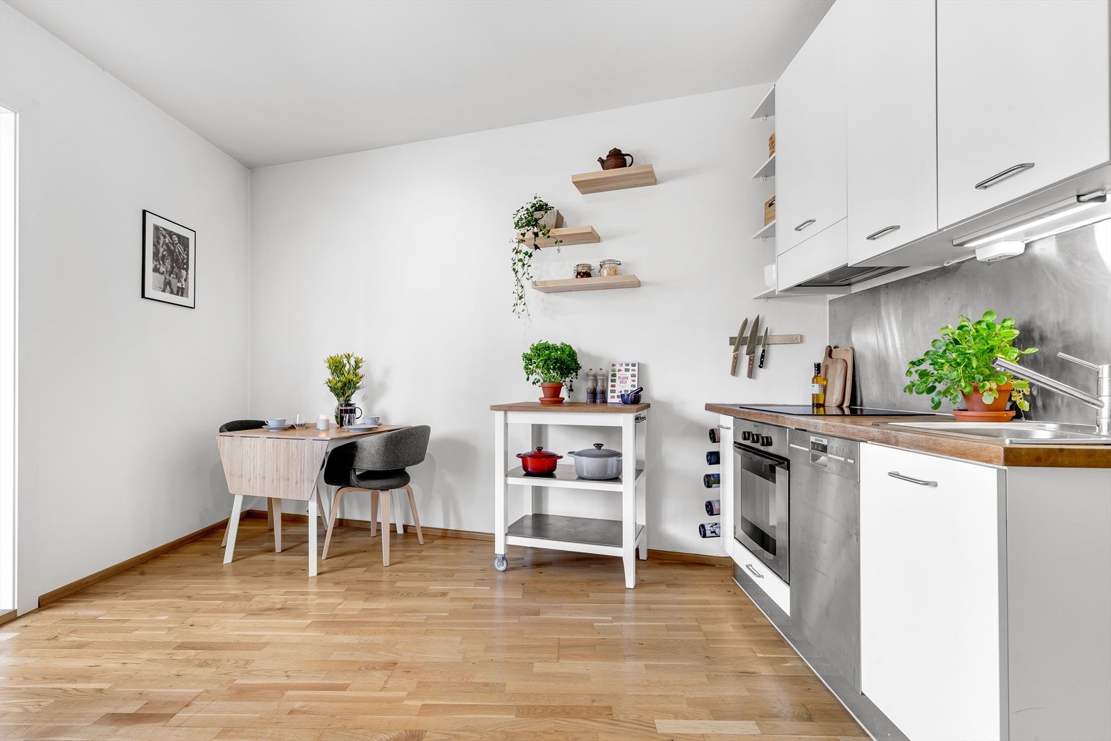 Kjøkkeninnredningen inneholder bla. børstet stålplate mellom overskap og heltre benkeplate, kum med ettgreps blandebatteri, kullfiltervifte over integrert koketopp/ovn og opplegg for oppvaskmaskin. Galleribilde