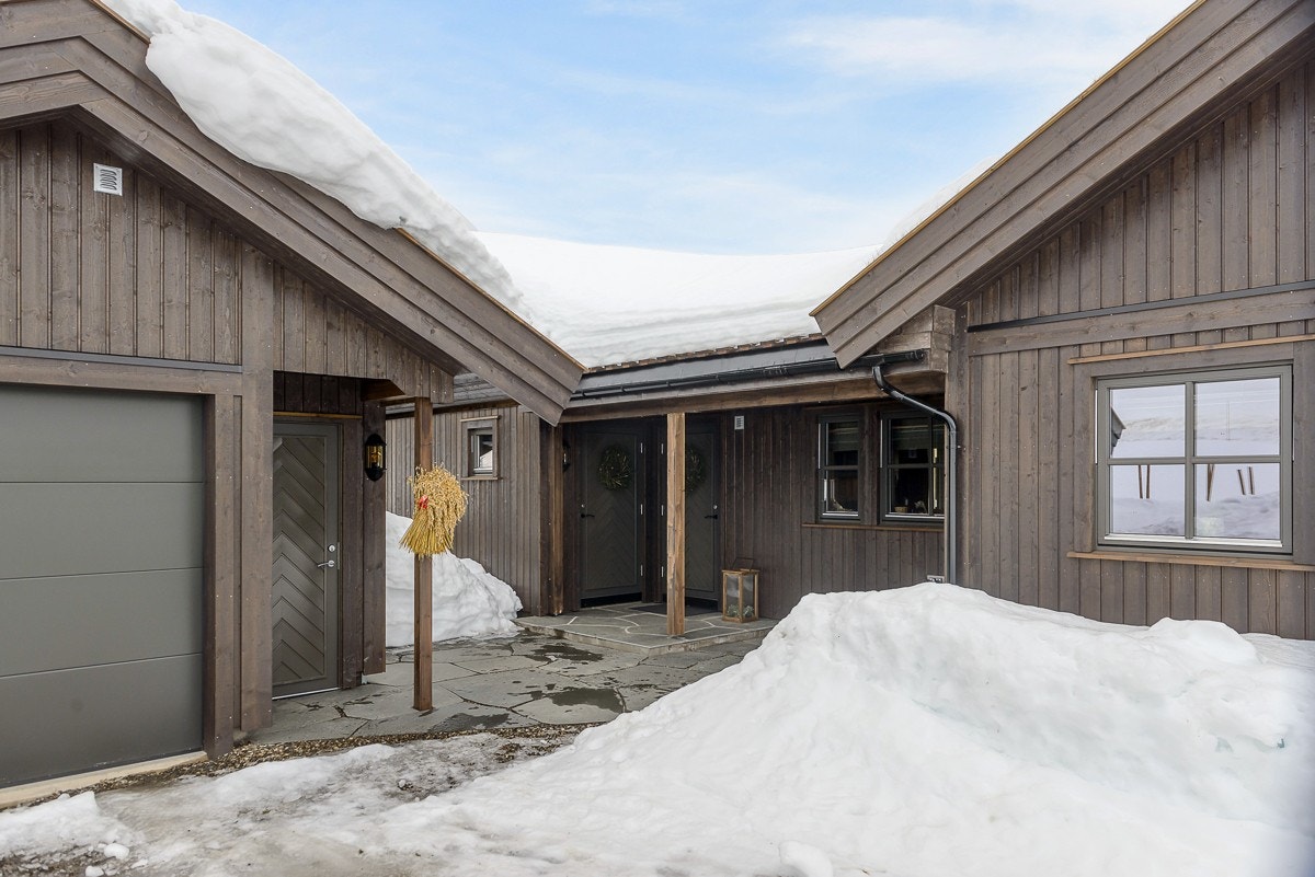 Mellom garasjen og hytta er det et skiferbelagt gårdsrom med belysning Galleribilde