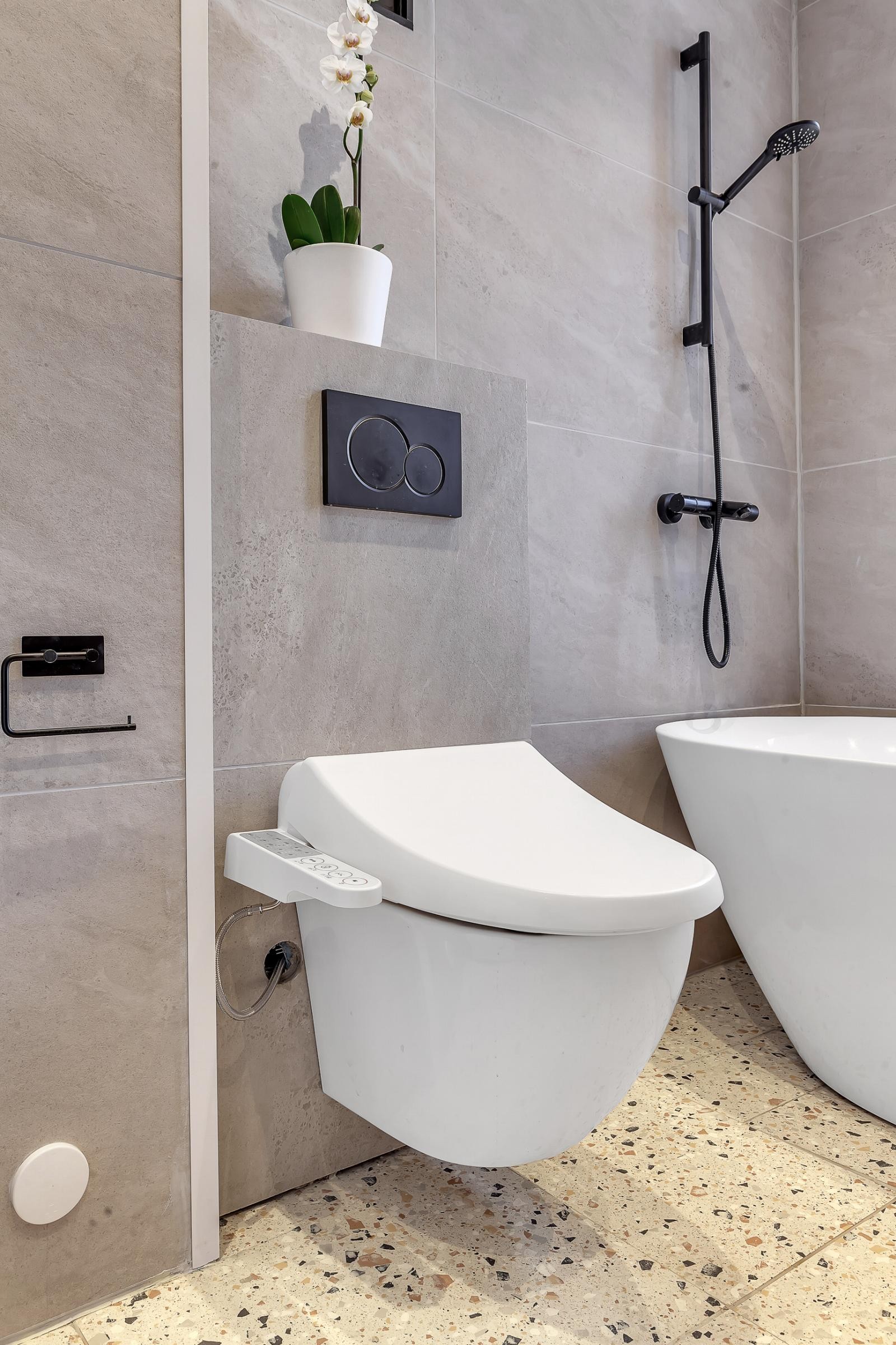 Vegghengt, japansk toalett med varme og spiler og stilrene fliser. Opplegg for vakemaskin. Galleribilde