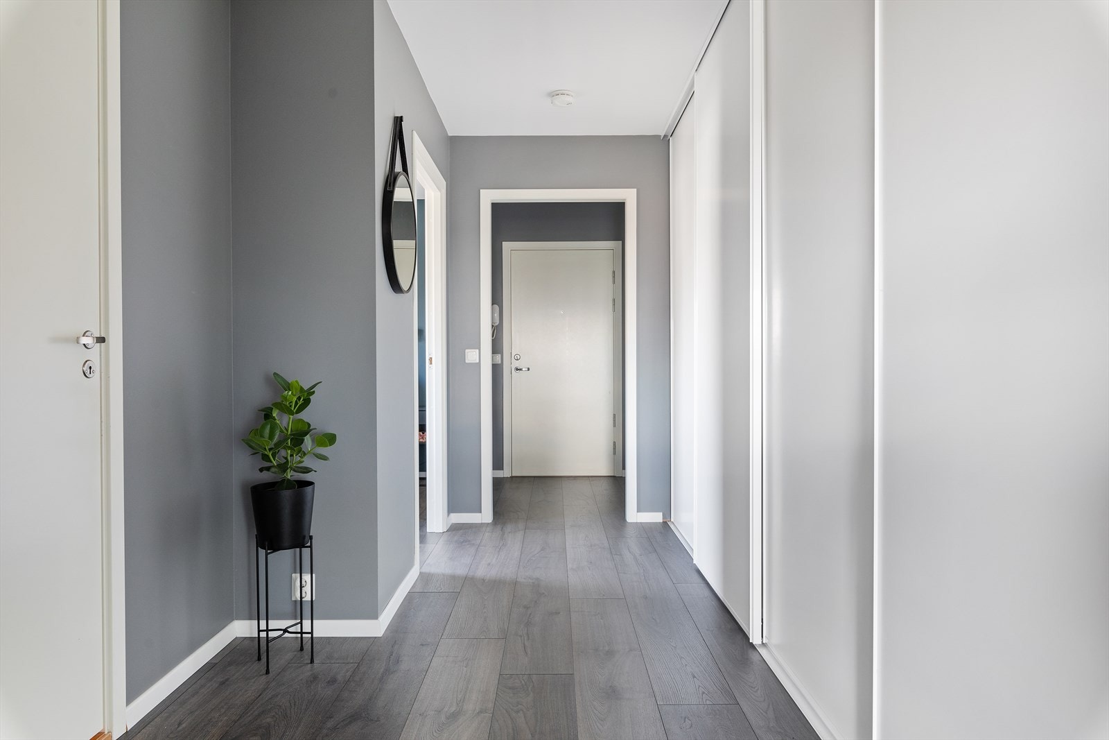 Leiligheten ligger i femte etasje og har adkomst via felles trapper eller heis. Boligen har en innbydende entré med lysmalte vegger i grå og laminat på gulvet. Galleribilde