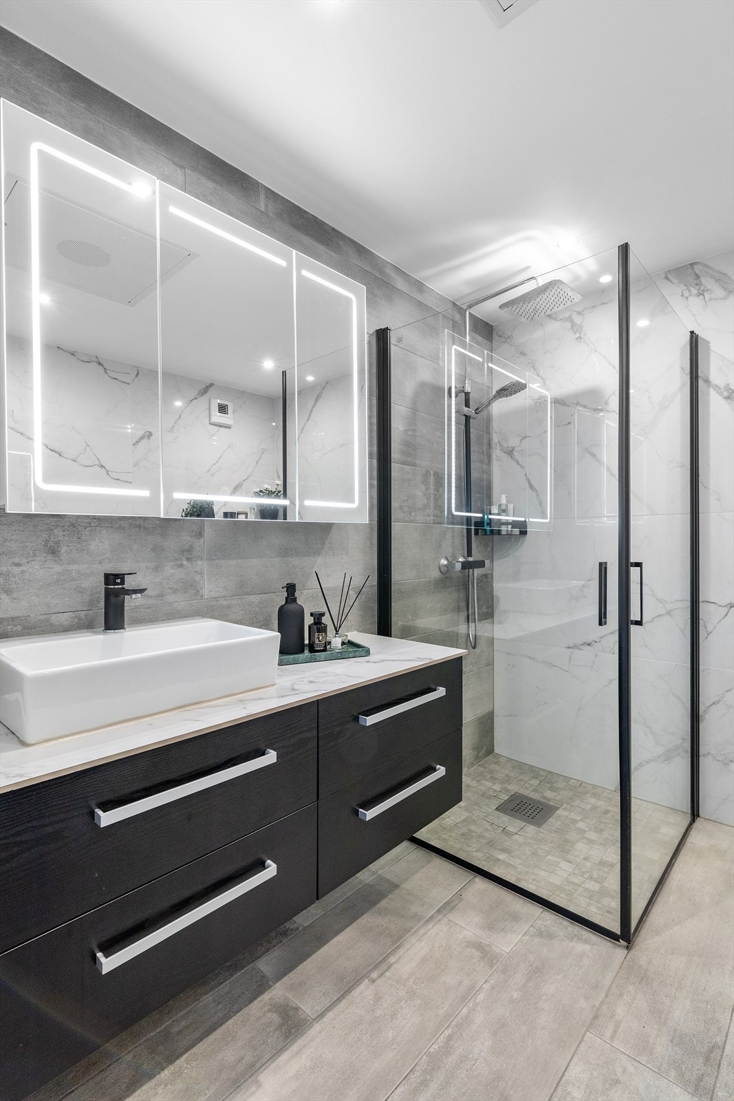 Badet har behagelig varme i gulv og downlights i himling. Servantskap og toalettskap med glatte, folierte fronter, dusjhjørne med rette svingdører og regnfallsdusj. Galleribilde