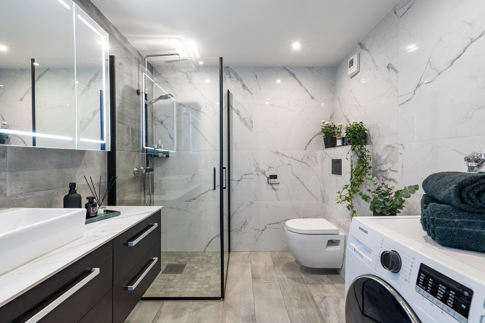 Leiligheten har et pent bad med moderne fliser på vegger og gulv. Galleribilde