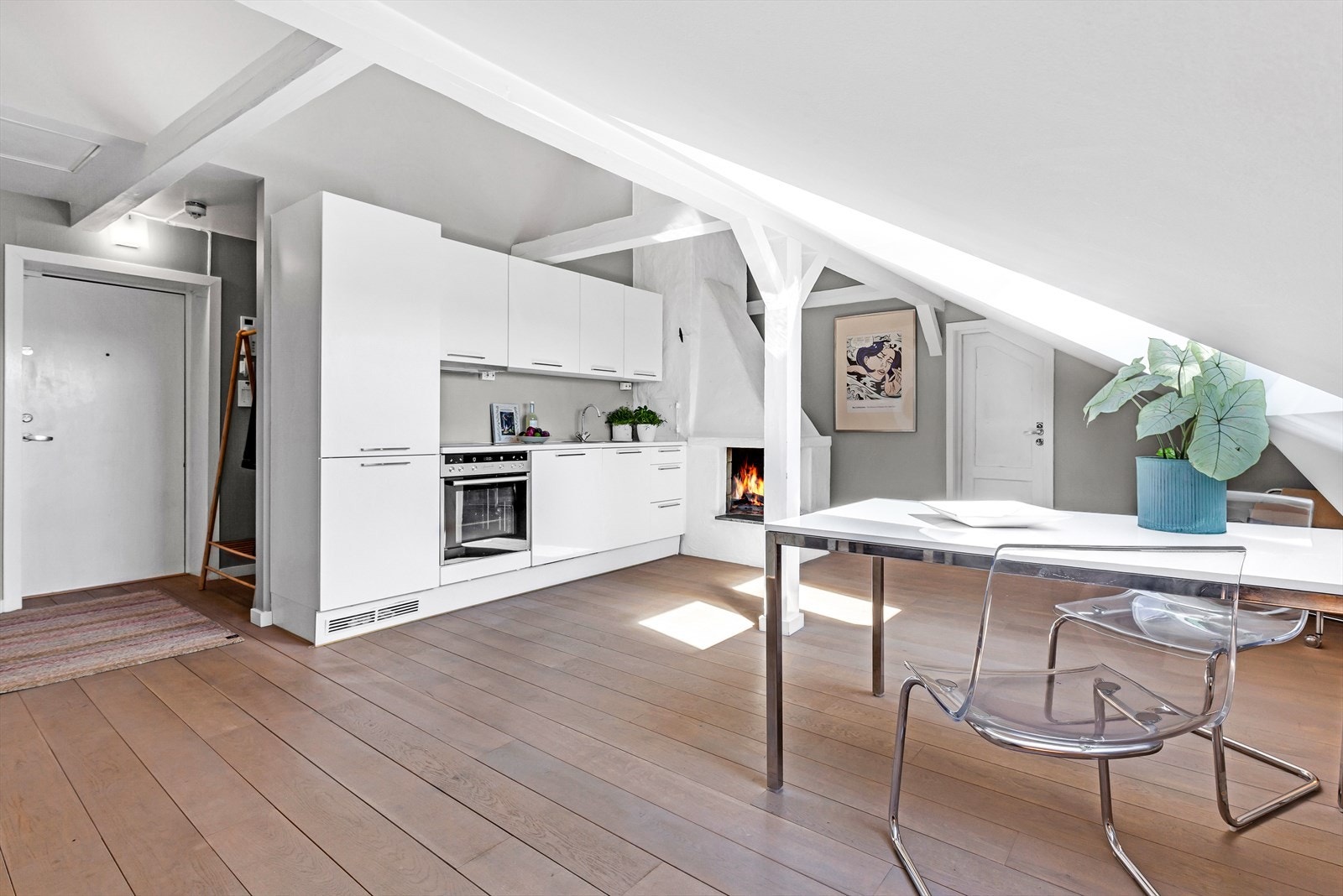 Kjøkkenet fra JKE-design har lys, glatt innredning, oppvaskkum og keramisk koketopp som er nedfelt i laminat benkeplater og avtrekksviften med kullfilter som er diskret plassert under overskap og over koke- og stekesonen. Galleribilde