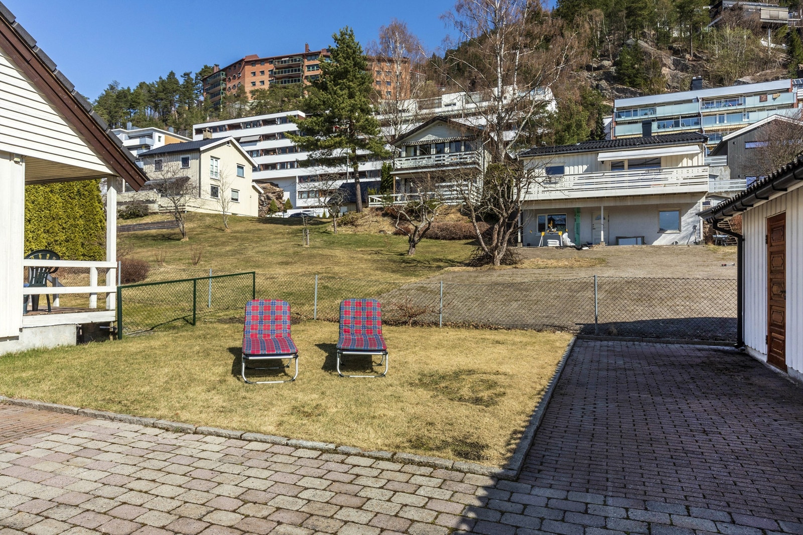 Koselig uteplass på baksiden av huset. Her sitter du i le og er godt skjermet. På de varmeste sommerdagene er dette en av favorittplassene ute. Til høyre i bildet ser du dør til boden som er i bakkant av garasjen Galleribilde