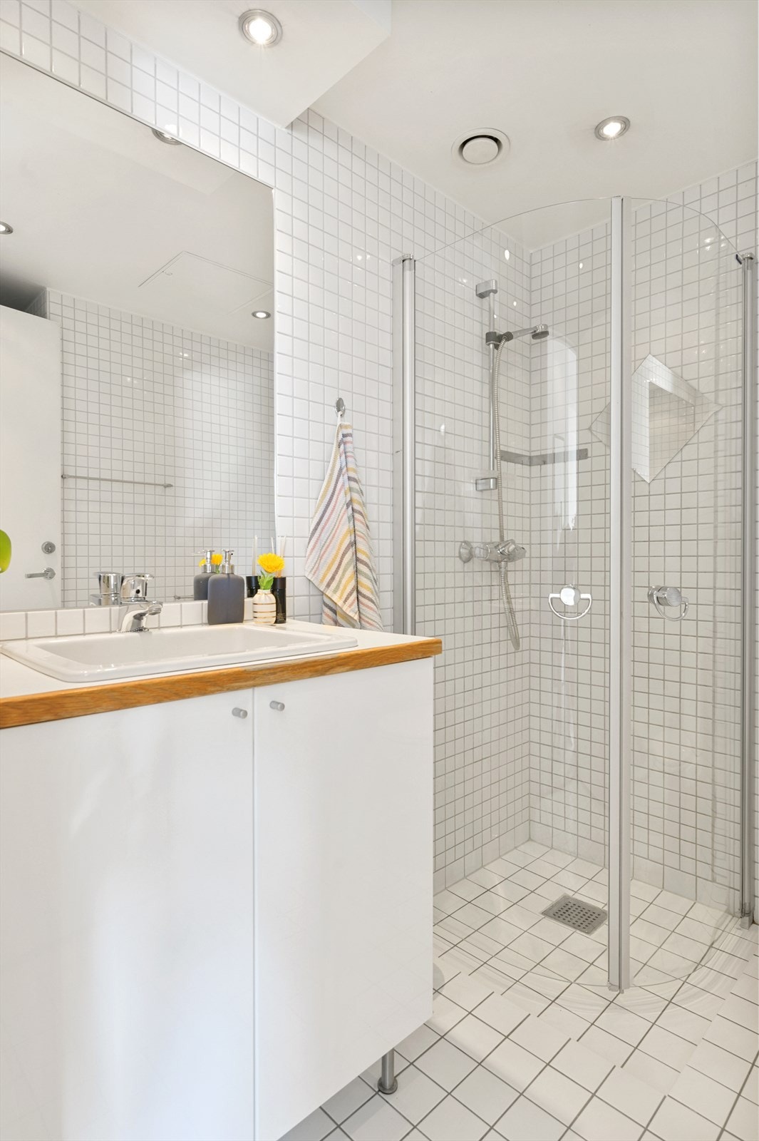 Servant nedfelt i laminat benkeplate
på benkeskap med glatte høyglansfronter. Speil, toalett og dusj i hjørnet bak svingbare glassvegger. Galleribilde