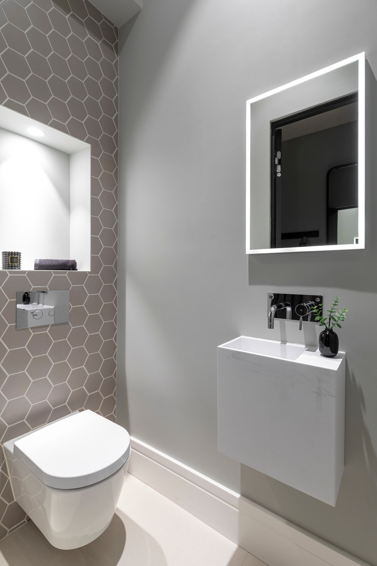 Adkomst fra entré til gjestetoalett med flislagt gulv og veggmontert servant i Corian Galleribilde