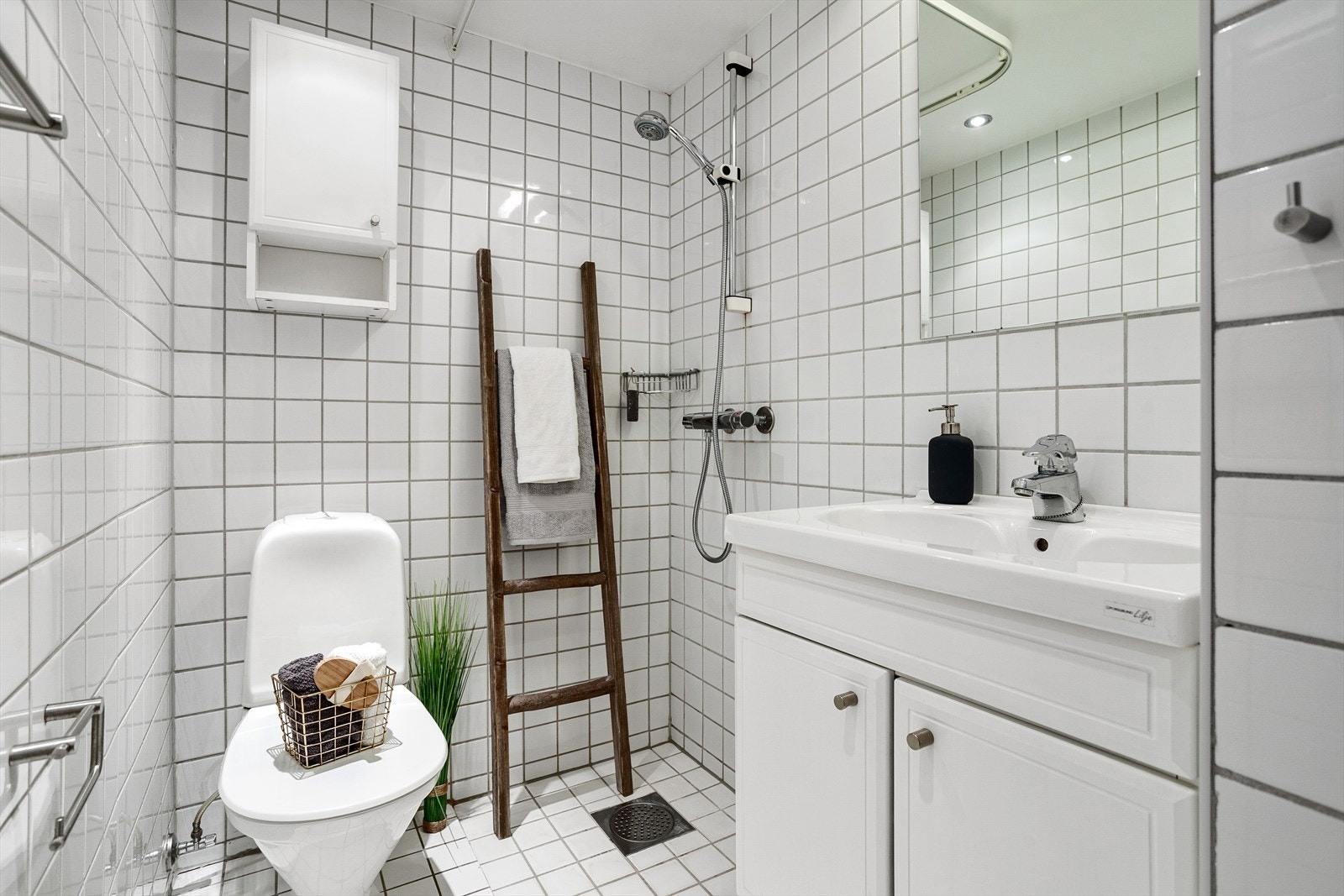 Badet inneholder vegghengt servantskap i profilert utførelse, ovenpåliggende servant med ett-greps armatur og speil med belysning over servant Galleribilde