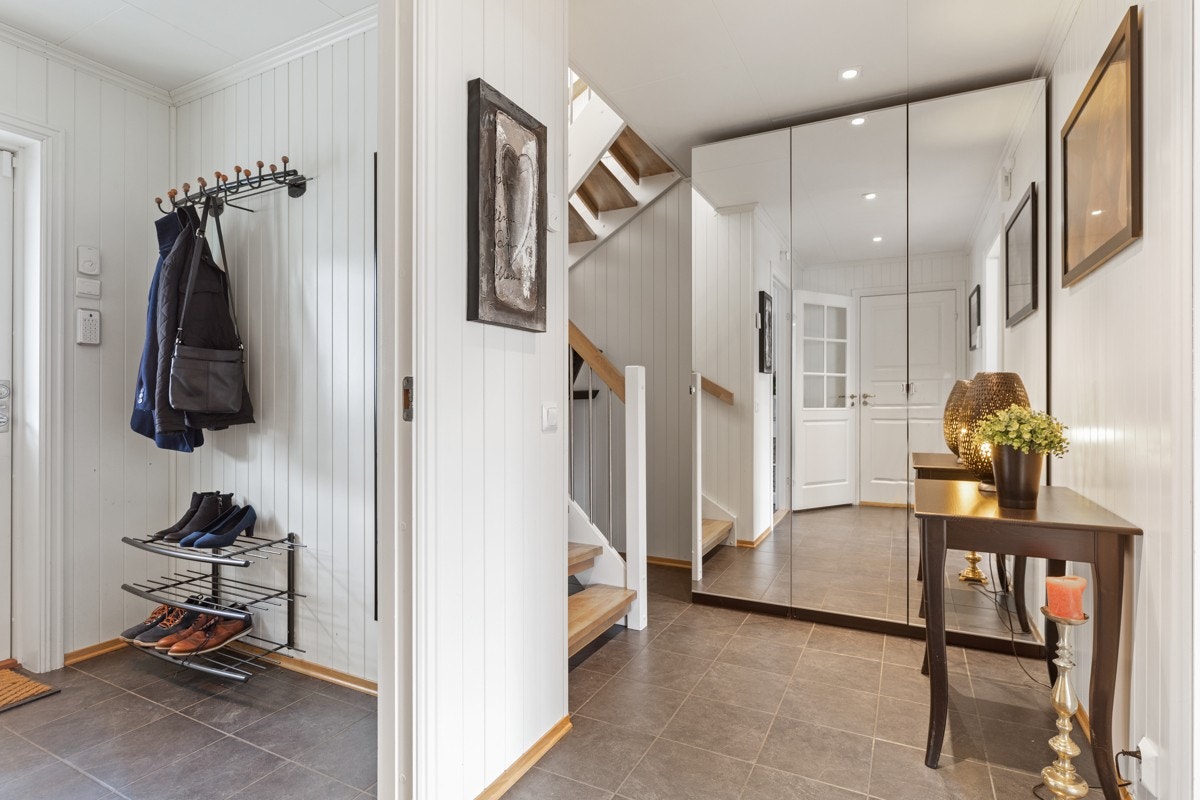 Entreen har fliser på gulv med gulvvarme og vegger med panel - en stil som strekker seg videre inn i trappegangen. Galleribilde