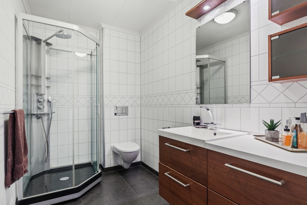 Rommet har nøttebrun innredning, dusjkabinett og vegghengt toalett. Galleribilde