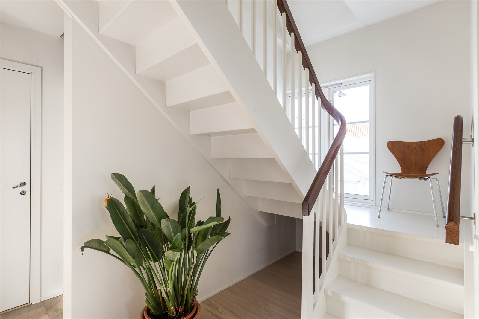 Lyst og lekkert trapperom, med walkin closet, med inngang helt til venstre i bildet. Galleribilde