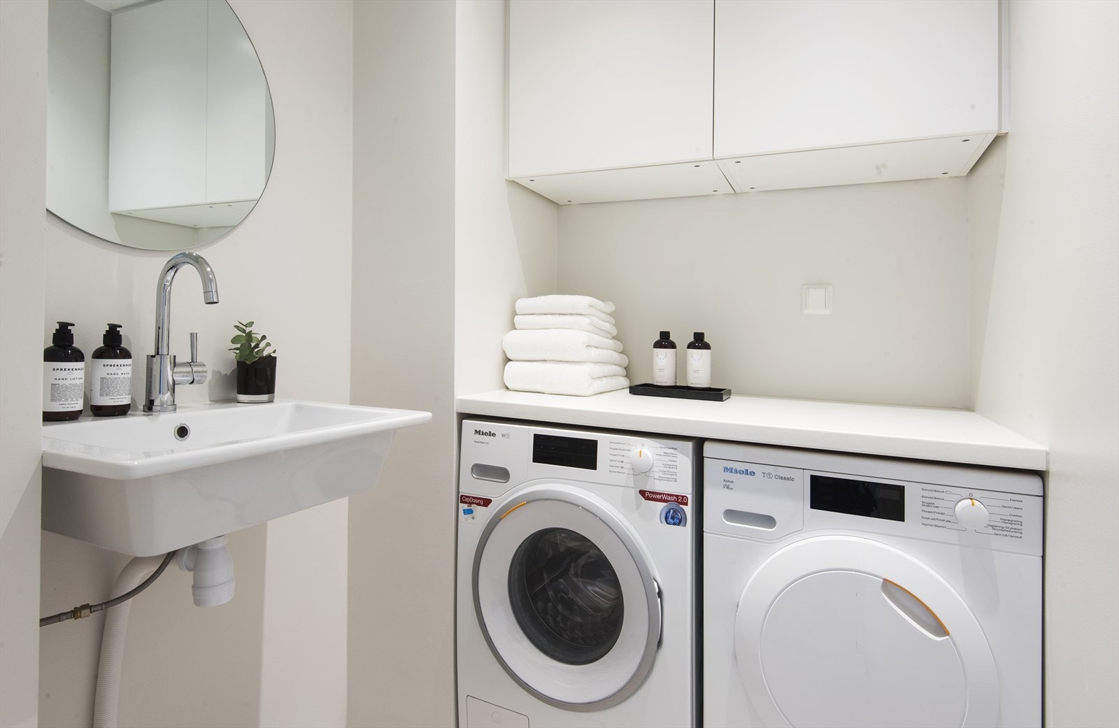 Vaskerom med opplegg for vaskemaskin, utslagsvask, benkeplate og overskap. Galleribilde