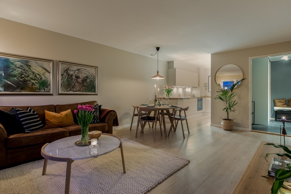 Kveldsbilde av stue med åpen løsning mot kjøkkenet. Galleribilde