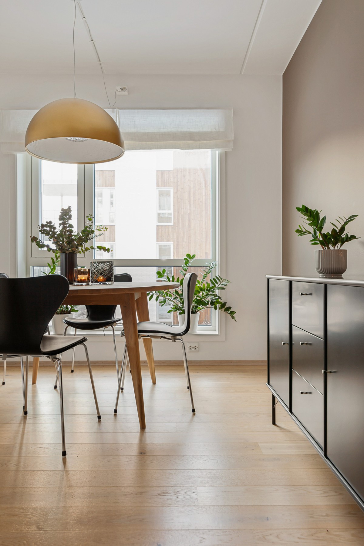 Spisebordet har sin plass like ved kjøkkenet. Store vindusflater slipper inn rikelige mengder med naturlig lys i rommet.