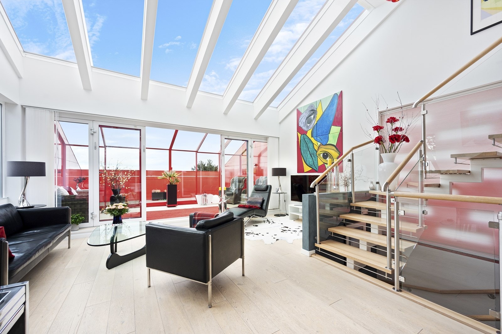 Stue har store glassflater i tak som slipper inn maksimalt med lys Galleribilde