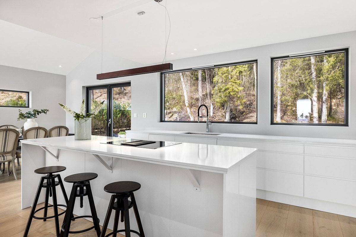 Ny kjøkkeninnredning med steinkompositt benkeplater, nedfelt oppvaskkum i rustfritt stål og flexiarmatur. Integrert Bosch mikrobølgeovn, stekeovn, induksjonstopp med kullfilterventilator, oppvaskmaskin, vinskap, kjøle og fryseskap. Galleribilde