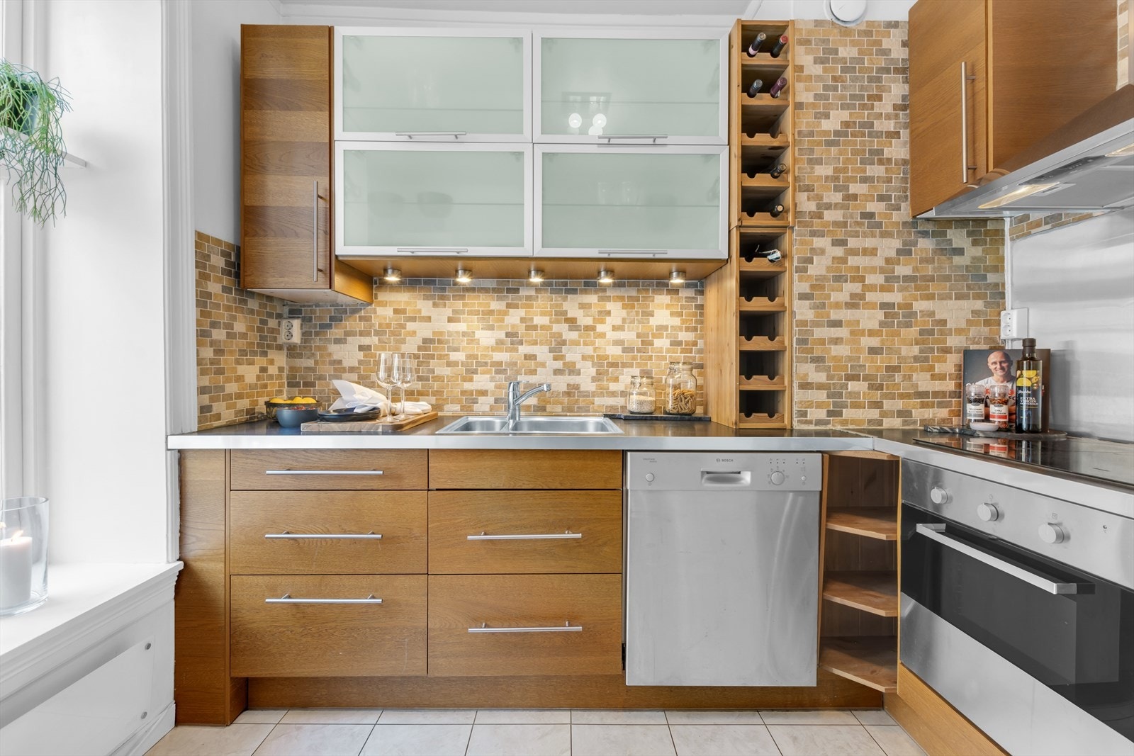 Fliser mellom kjøkkenbenk og overskap. Benkeskapsbelysning og stikkontakter over kjøkkenbenk Galleribilde