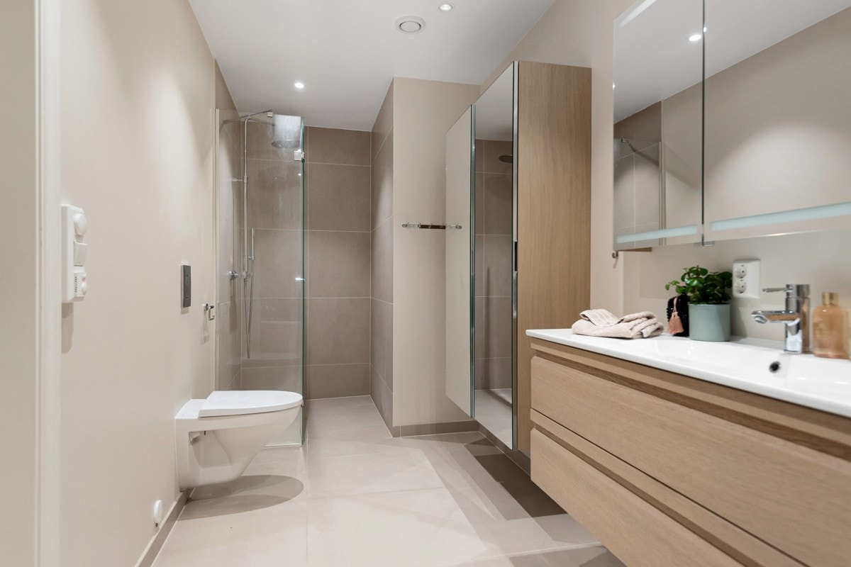 Det største badet har adkomst fra gangen. Baderomsinnredningen består av speilskap med integrert belysning, skuffeseksjon med heldekkende servant og et vegghengt høyskap med speildører. Galleribilde