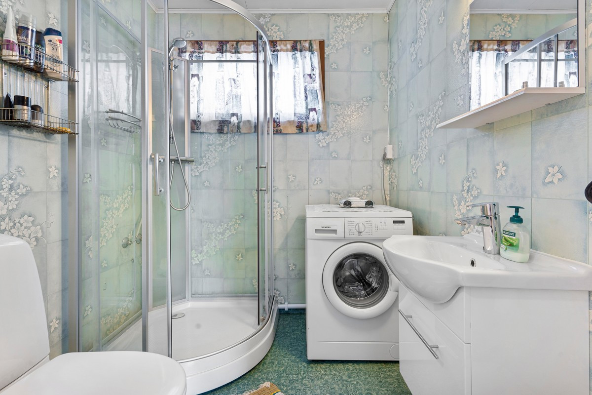 Badet er innredet med dusjkabinett, toalett og servant - i tillegg er det opplegg for vaskemaskin