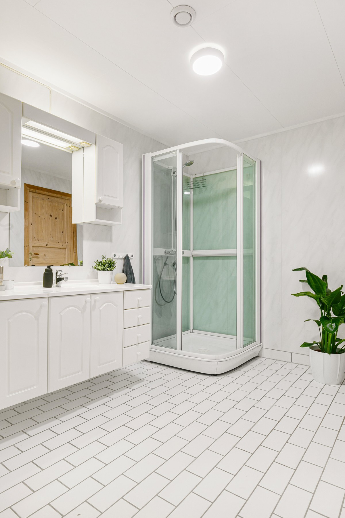 Badet er utstyrt med dusjhjørne og servant