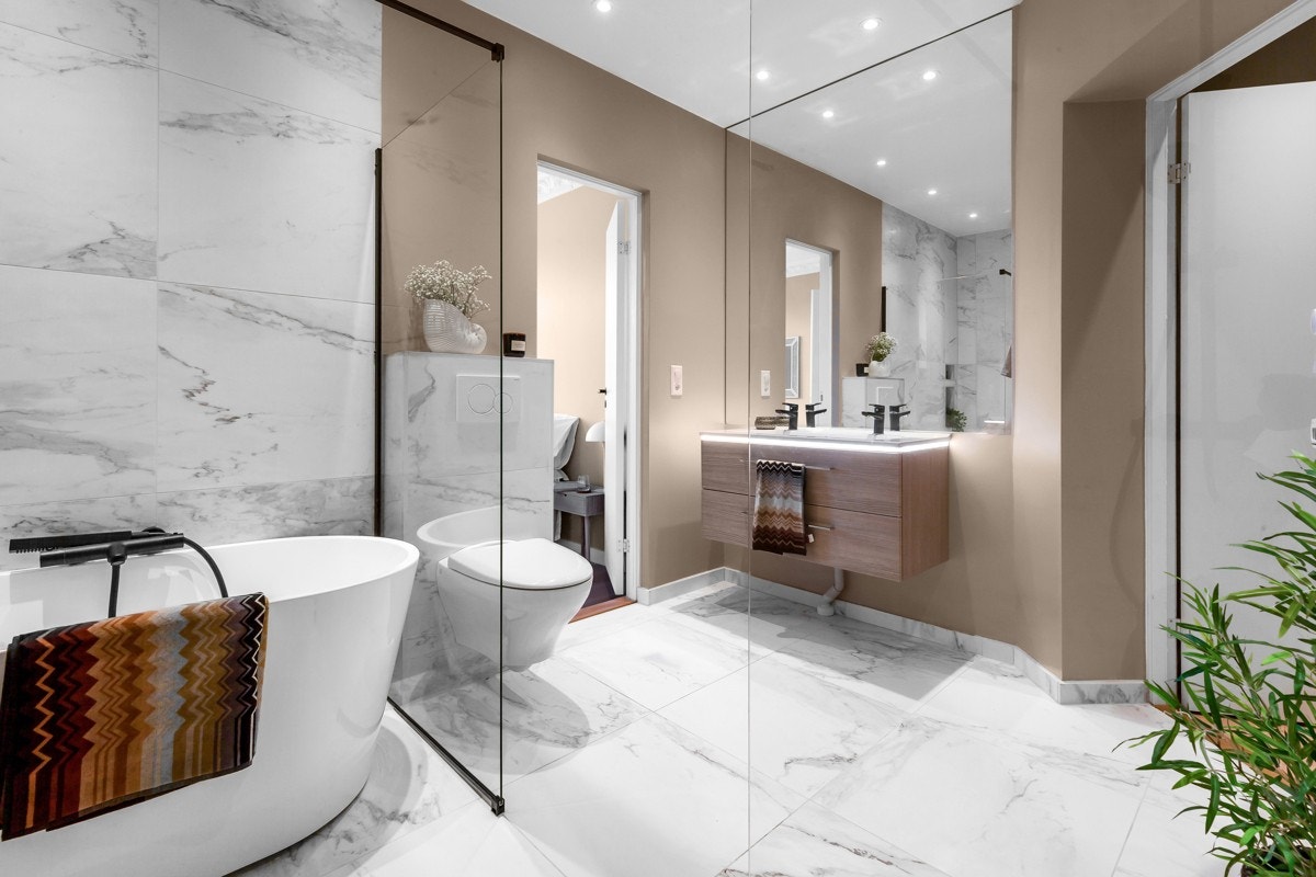 Lekkert, flislagt baderom (Calacatta Smooth fliser) med varme i gulv, noe som gir en lun og god start på dagen Galleribilde