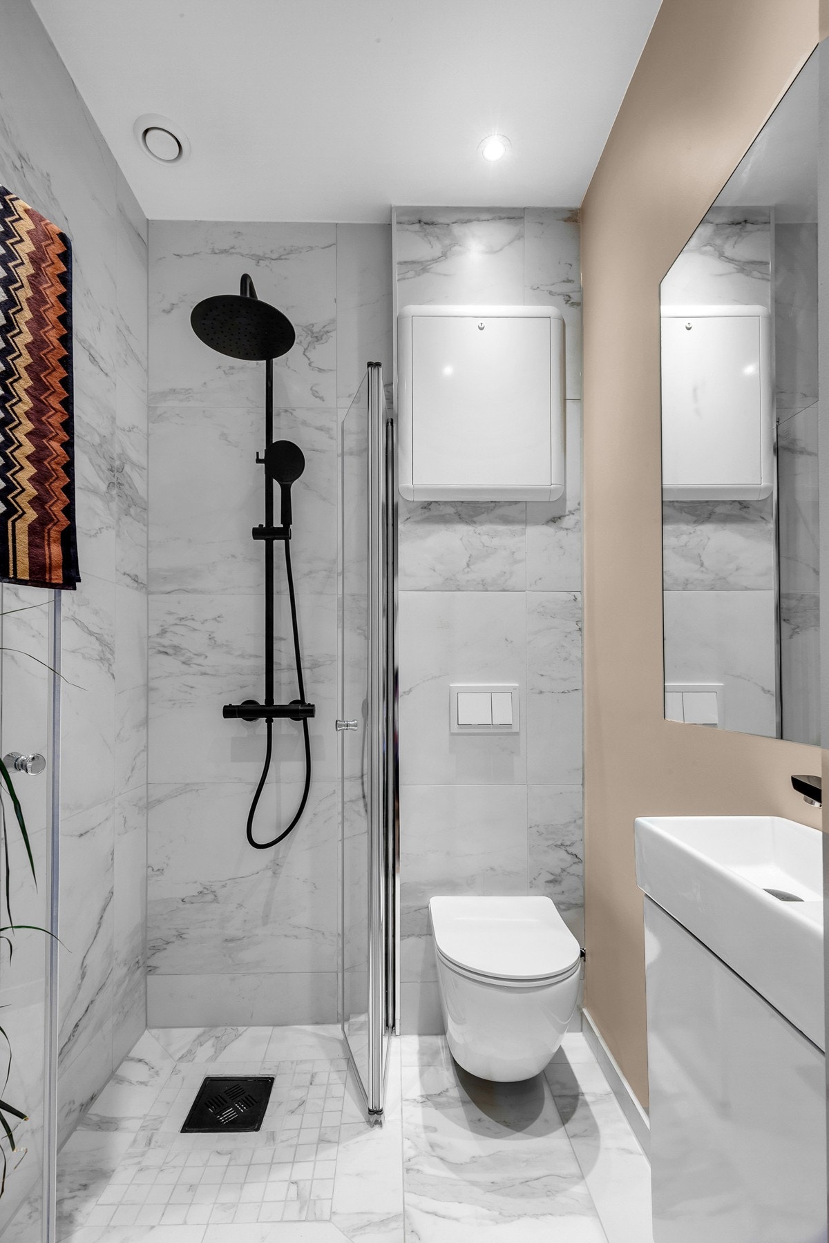 Flislagt baderom med dusjhjørne, vegghengt toalett og servant på underskap Galleribilde