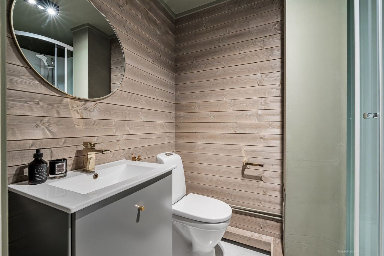 Badet har også grå innredning, wc, servant, servantskap, dusjkabinett og opplegg til vaskemaskin. Galleribilde