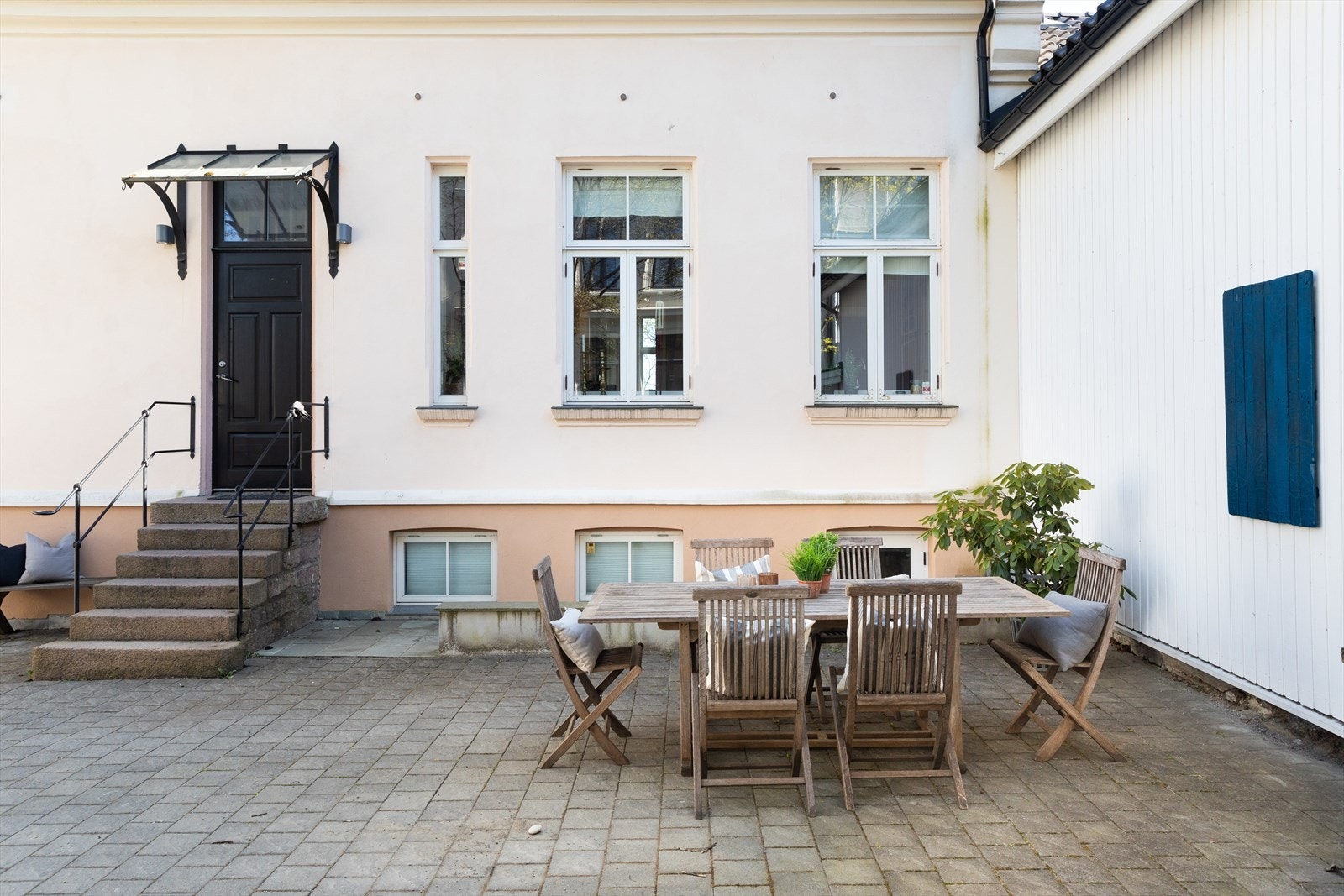 Stor gårdsplass med én hovedentré og inngang til hybel i underetasje. Galleribilde