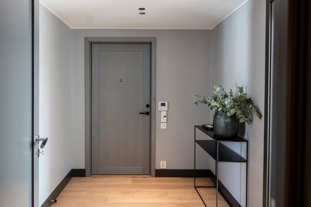 Den massive finerte ytterdøren fører deg inn i en omfangsrik entré som gir et meget godt førsteinntrykk og en smakebit på den høye kvaliteten og gjennomførte stilen som preger leiligheten. Galleribilde