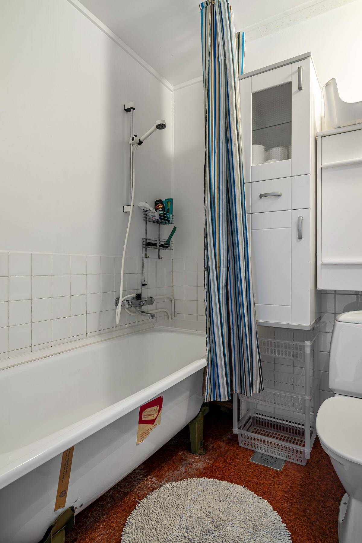 Badet inneholder badekar, gulvmontert toalett og servant med speil