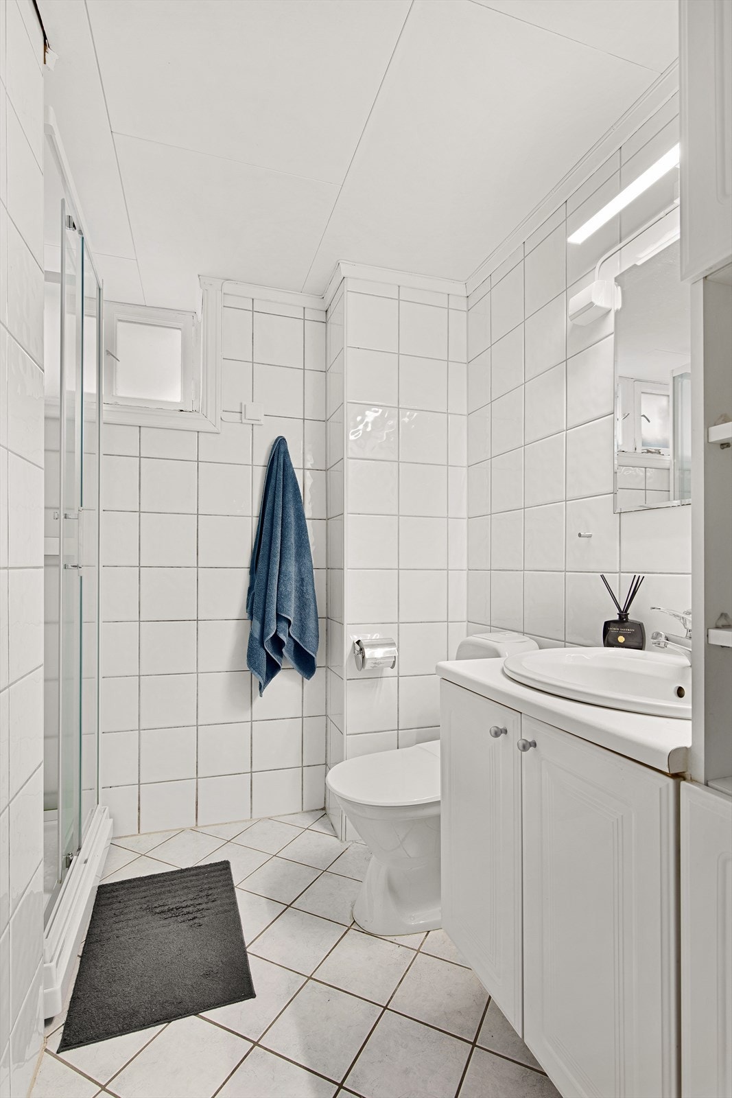 Flislagt bad innredet med servant i innredning, toalett samt dusjkabinett Galleribilde