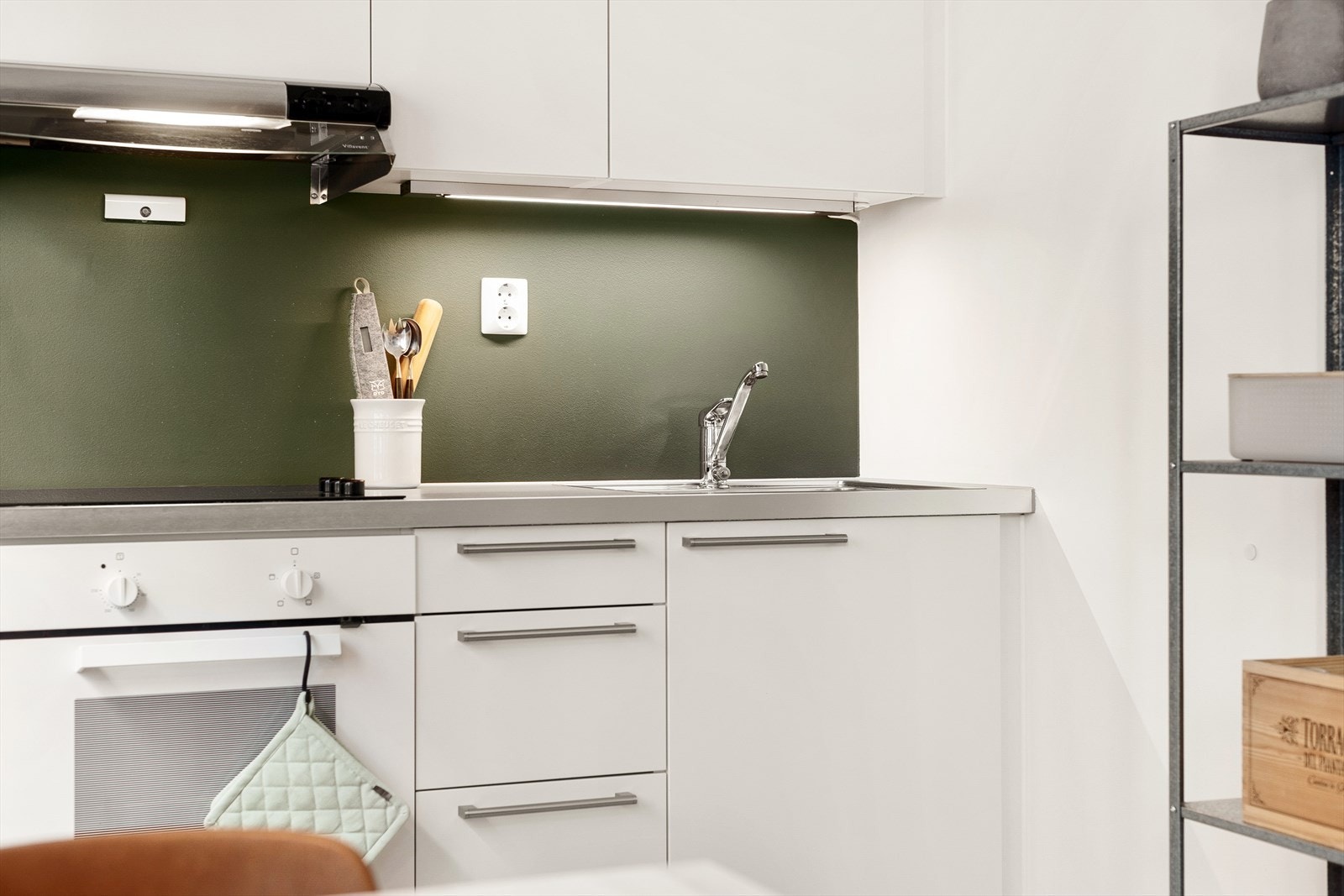 Over kjøkkenbenk er veggen malt i en dus grønn tone som harmonerer godt med de øvrige fargene i leiligheten. Galleribilde