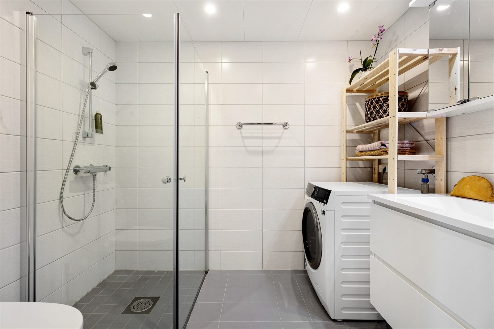 Lekkert flislagt bad servantinnredning, vegghengt toalett og dusjhjørne. Galleribilde