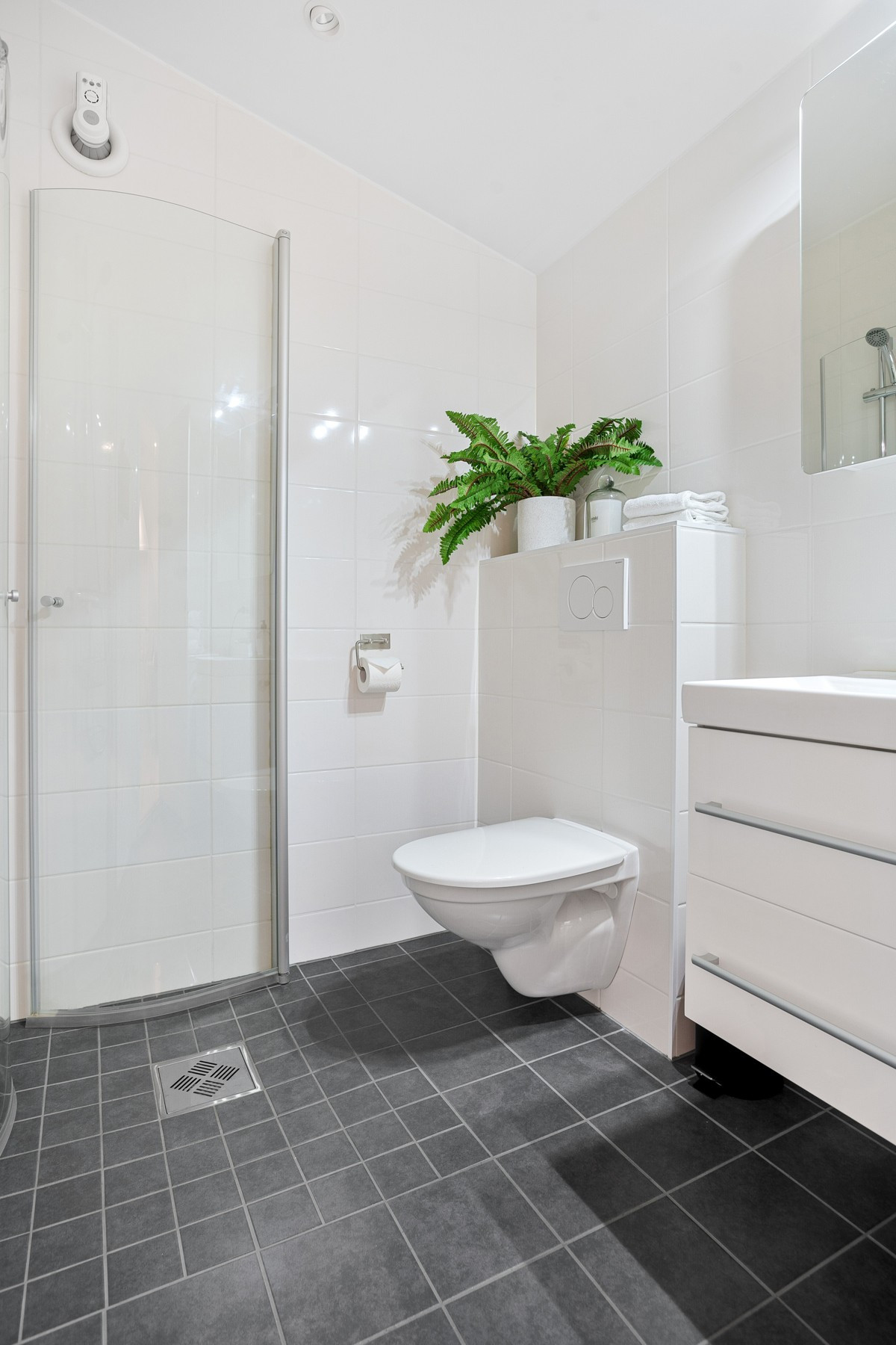 Badet er utstyrt med vegghengt toalett, servant m/ tilhørende underskap og dusj,