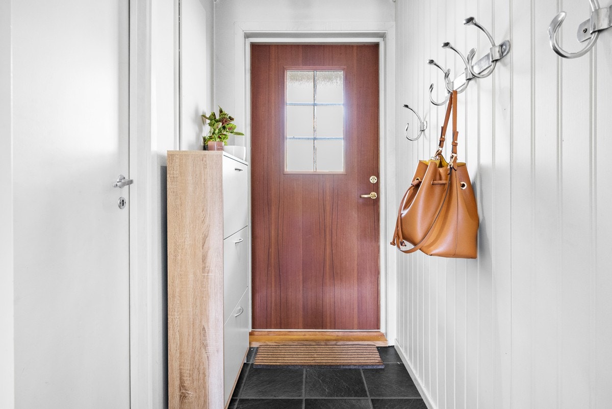 Du entrer leiligheten inn i et lyst og trivelig vindfang. Her er det montert opp et praktisk skoskap samt noen knagger for å kunne legge til side yttertøy. Galleribilde