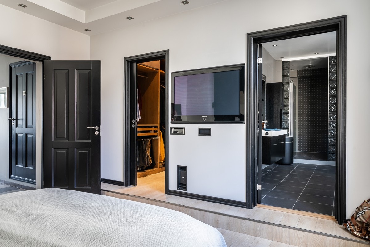 Innbygd TV samt inngang til omkledningsrom og bad fra soverommet Galleribilde