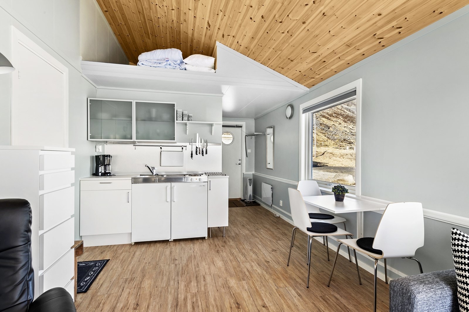 Enkel kjøkkeninnredning i rorbu/båthus med praktisk sovehems over. Galleribilde