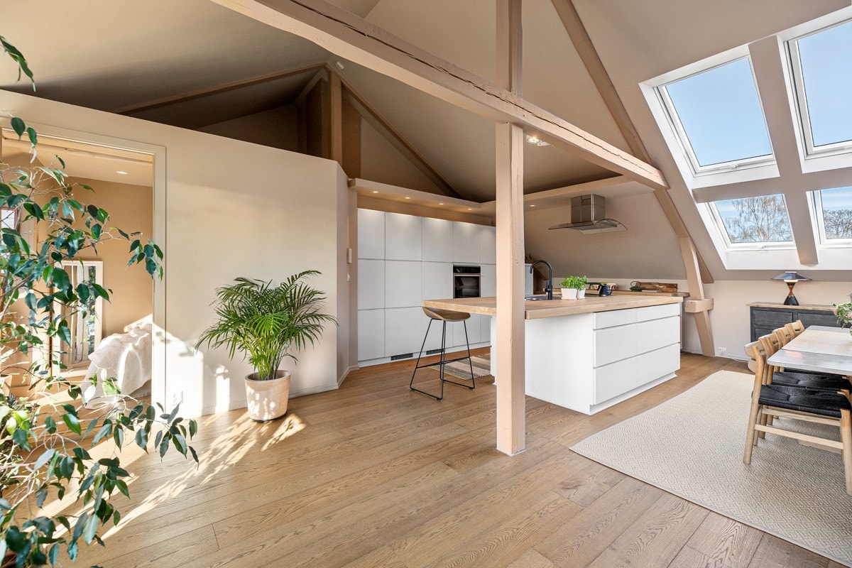 I leilighetens loftetasje er det stue/kjøkken i åpen løsning - et lyst og luftig rom med spennende detaljer. Galleribilde