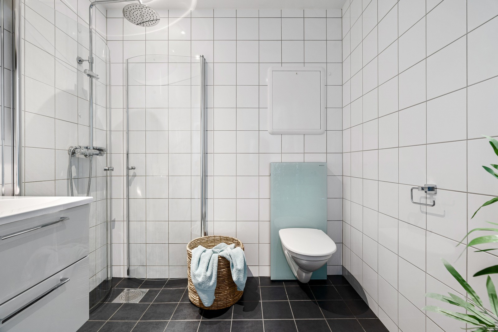 Badet er stort og komplett flislagt. Vegghengt toalett, servant med tilhørende speiler og dusjhjørne med regnfallsdusj og innfellbare glassdører