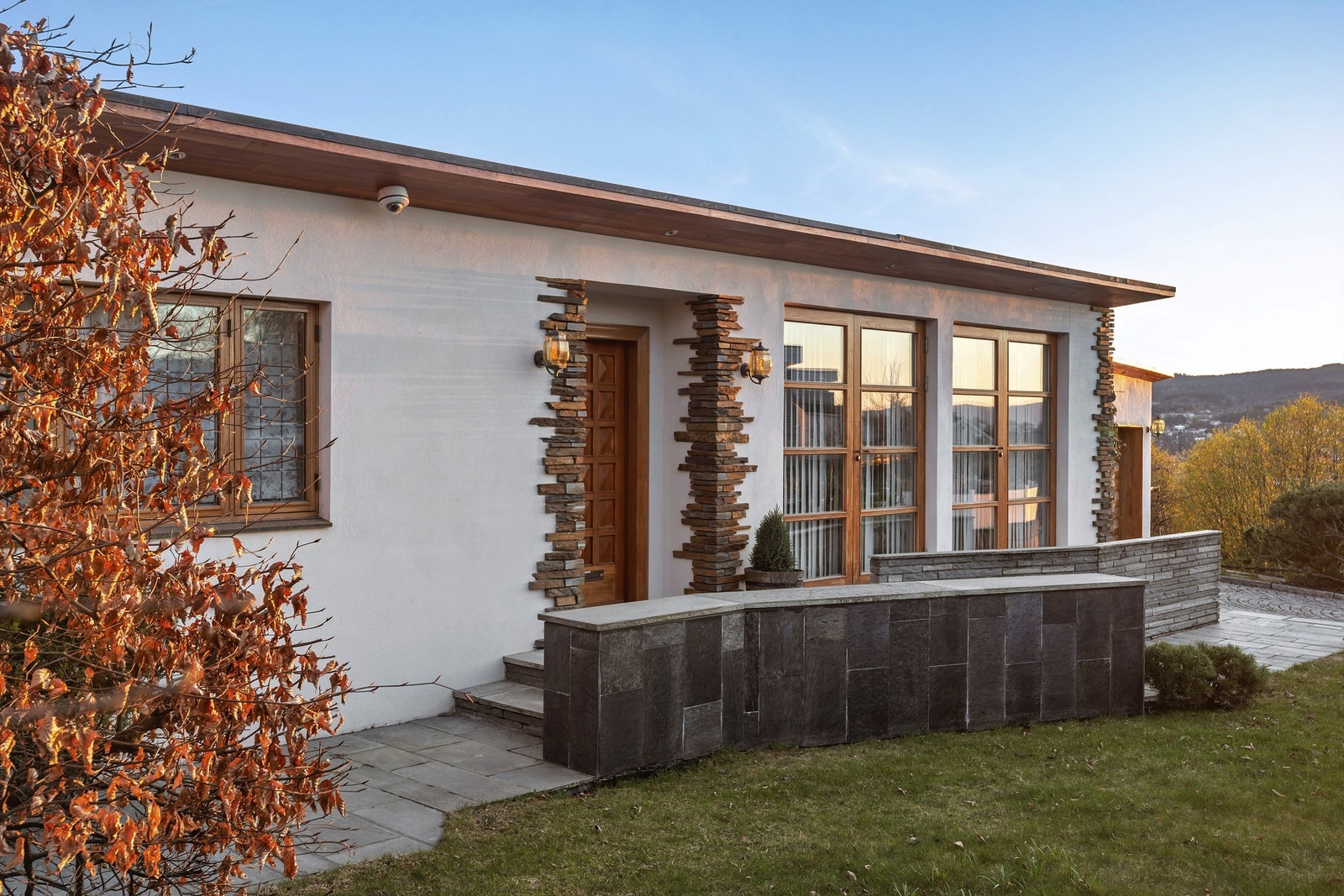 Boligens fasade preges av påkostede detaljer og stemningsfull utebelysning. Galleribilde