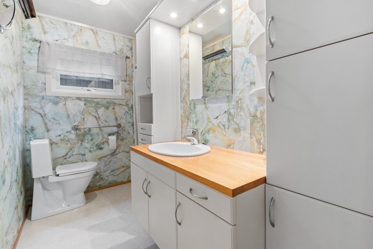 Baderom hovedetasje med dusjnisje, wc, og servant i hvit baderomsinnredning Galleribilde