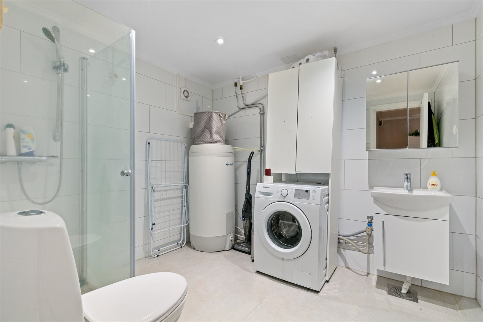 Baderommet er innredet med gulvstående toalett, dusjbatteri og dusjutstyr, skjermet dusjhjørne av herdet glass, speilskap, servant med underskap og ettgreps blandebatteri, gulvstående høyskap. Det er installert opplegg for vaskemaskin. Galleribilde