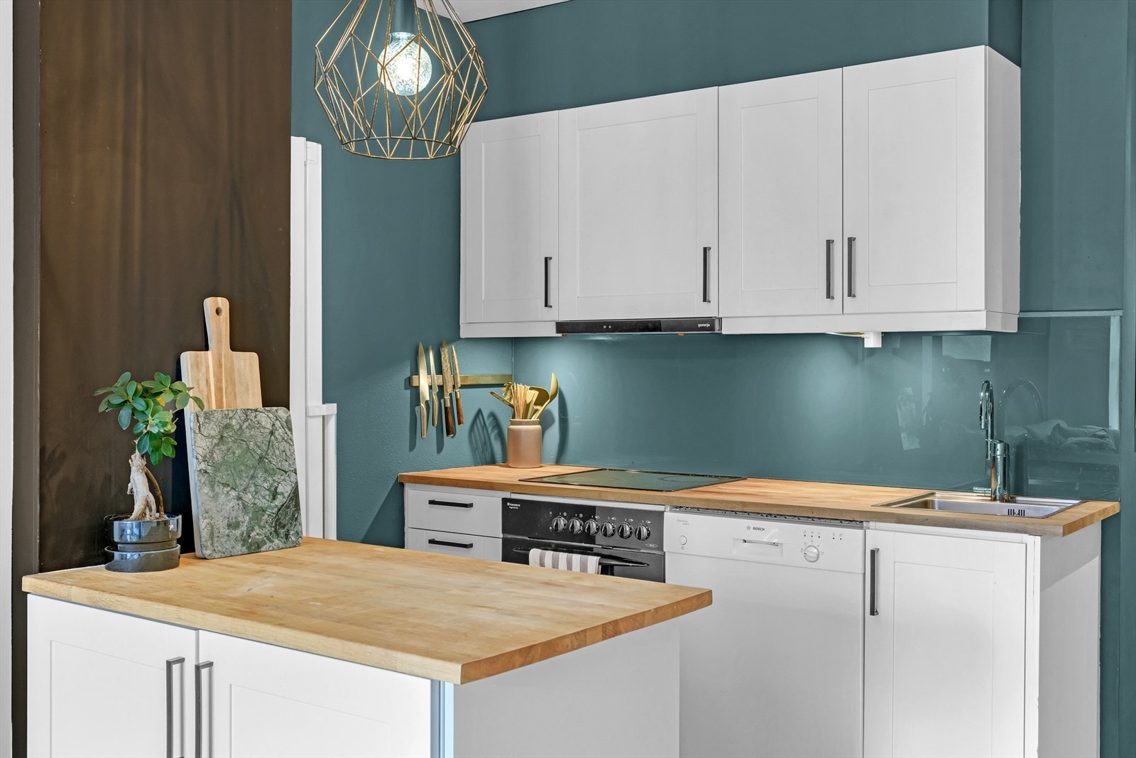 Åpen kjøkkenløsning. Kjøkkeninnredning fra 2006 med profilerte fronter. Benkeplate av tre. Glassplate på vegg samt benkeskapsbelysning over kjøkkenbenk. Galleribilde