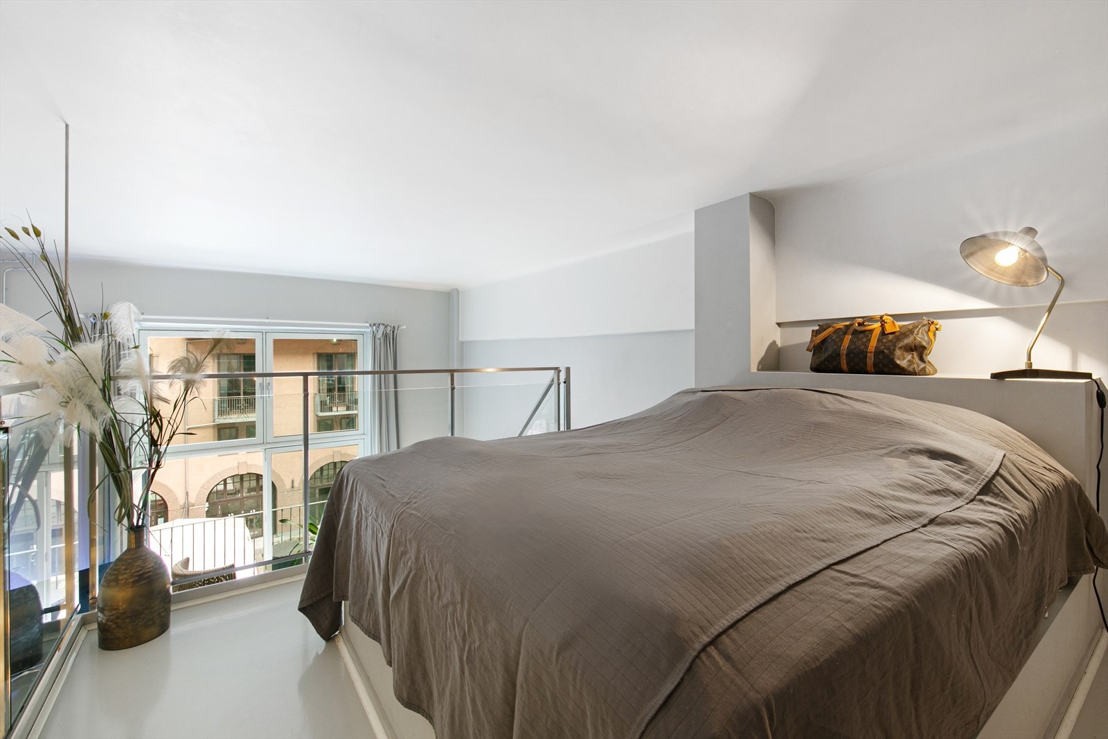 Mesanin brukes til soveplass. Glassrekkverk rundt kanter så man kan nyte utsikten ut mot balkong og gårdsrom Galleribilde