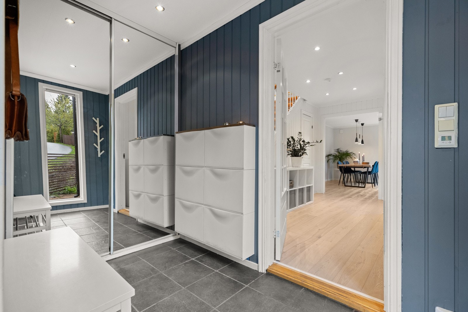 Entré med flislagt gulv, gulvvarme, downlightsbelysning og skyvedørsgarderobe med speilfronter. Galleribilde