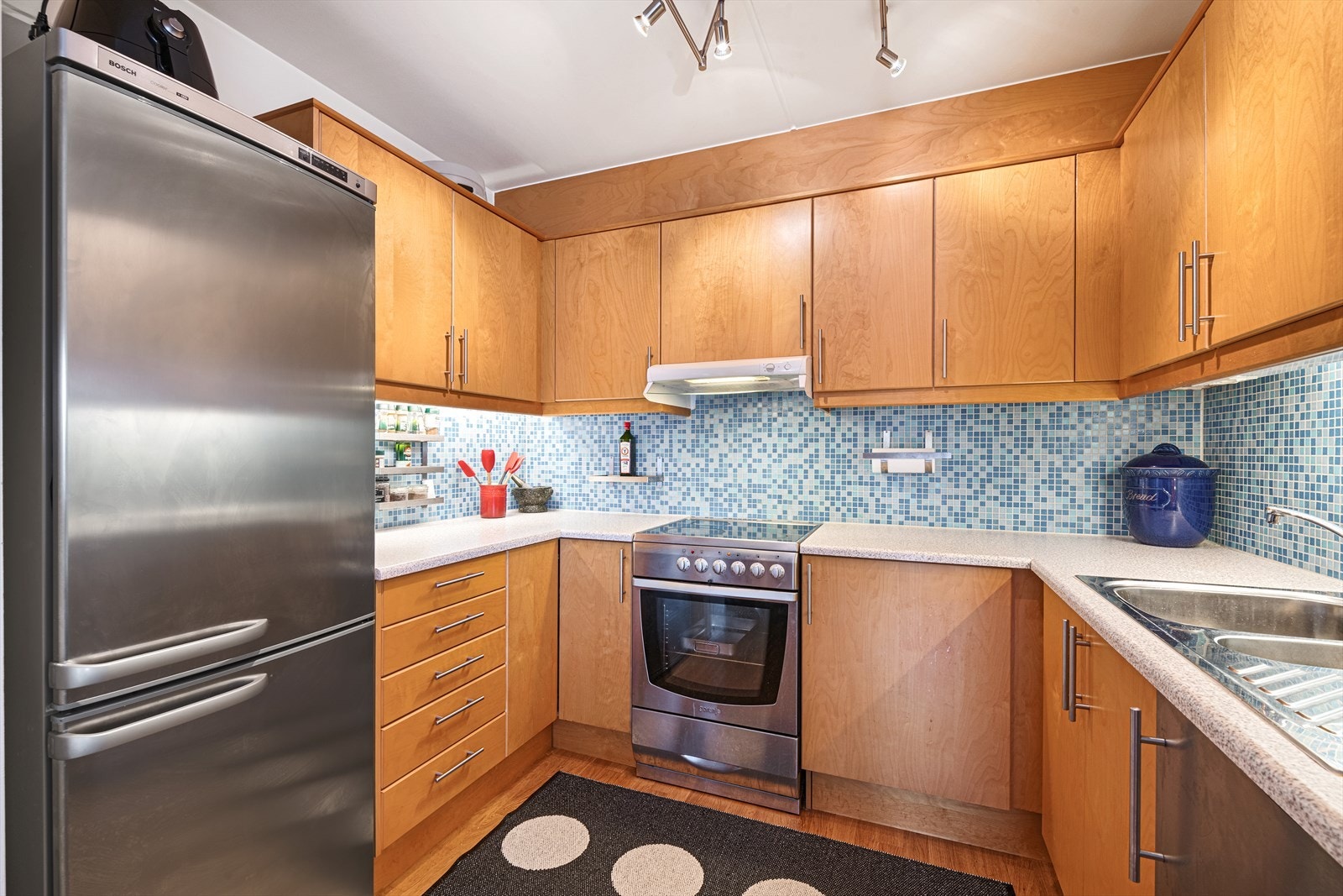 Kjøkkeninnredning med laminert benkeplate med nedfelt dobbelt oppvaskkum med 1-greps blandebatteri. Det er opplegg for oppvaskmaskin(ikke montert), komfyr og det er tilkoblet en ventilator over kokeplass. Galleribilde