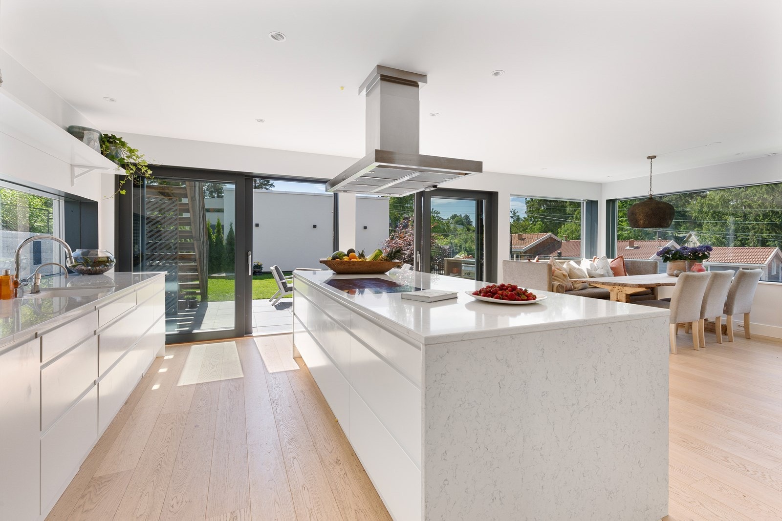 Lekkert kjøkken med hvite glatte fronter og benkeplate av steinkompositt. Galleribilde