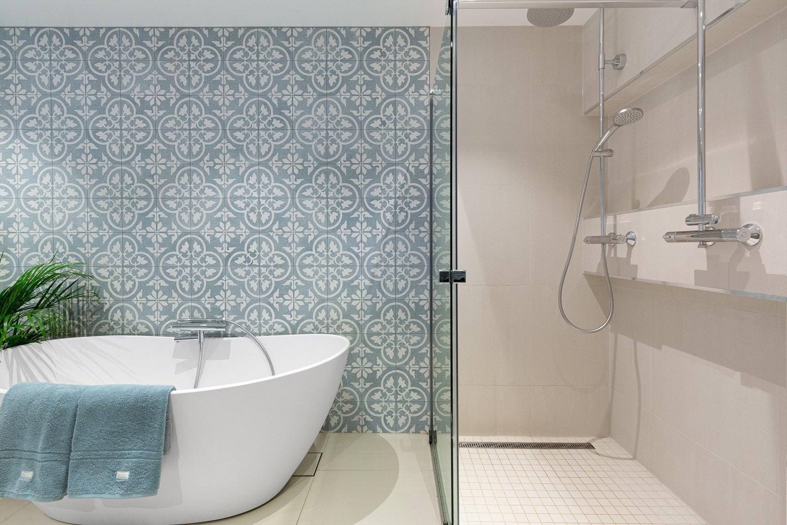 Badet har badekar med hånddusj, dobbel regndusj, vegghengt toalett med bidefunksjon og servantinnredning Galleribilde