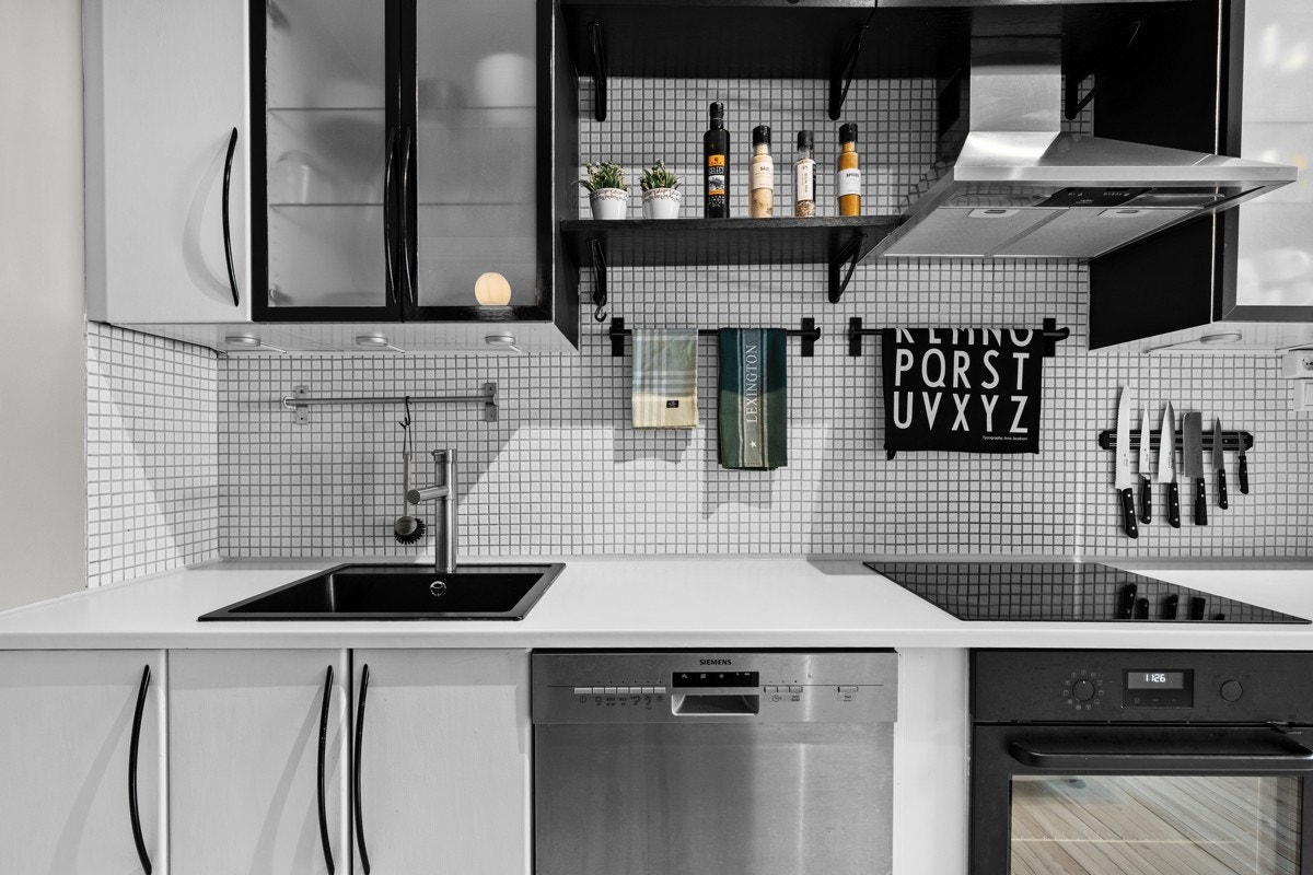 Det er pent flislagt med mosaikk mellom kjøkkenbenken og overskap, og belysningen under overskapene sørger for gode arbeidsforhold. Galleribilde