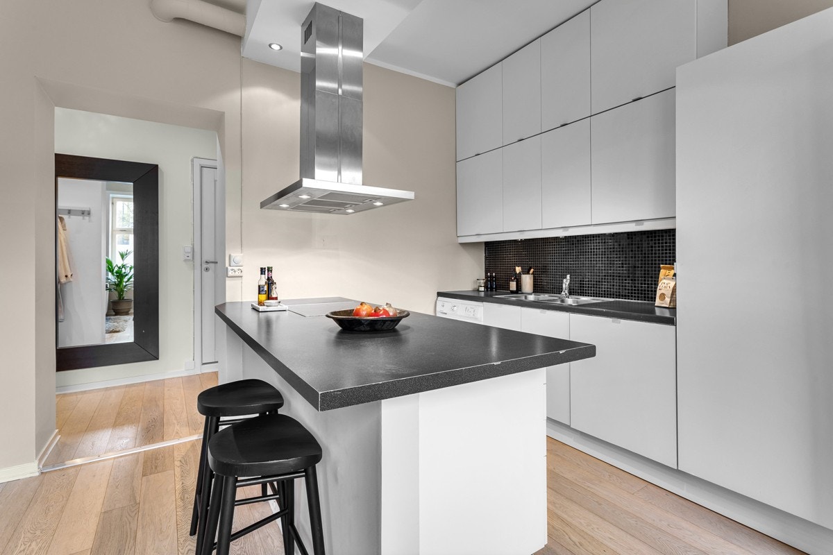 Kjøkkenøy med integrert platetopp og stekeovn fra Electrolux samt takmontert avtrekksvifte og oppvaskmaskin Galleribilde