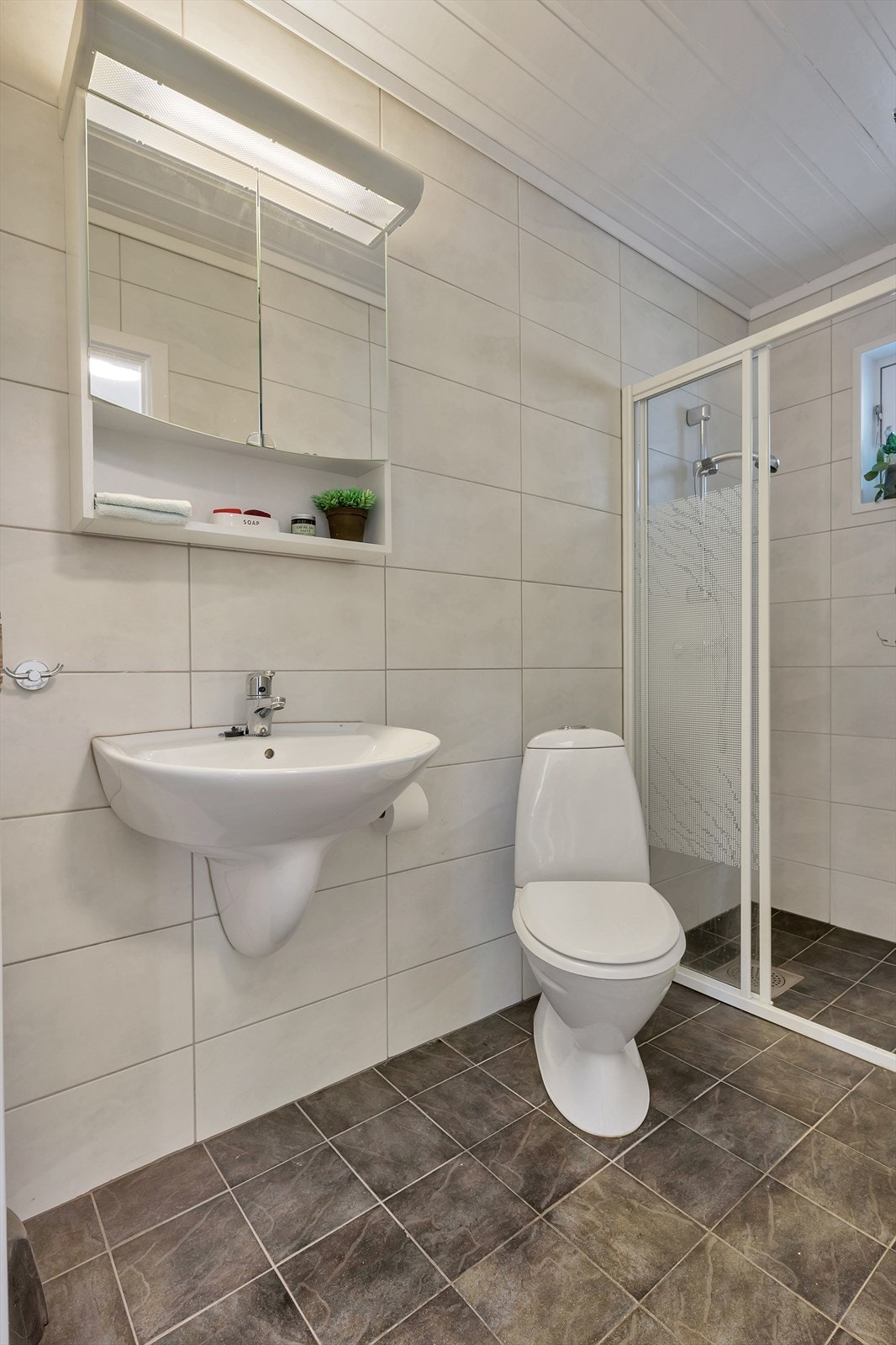 Flislagt bad i 1.etasje med dusjsone, toalett og servant Galleribilde